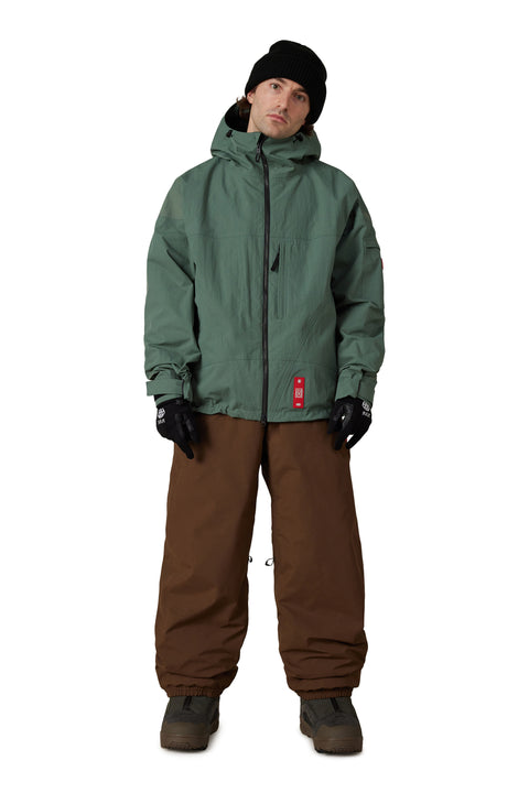 686 Men's Dojo Gore-Tex Shell Pant in brown, worn with green jacket and black beanie
