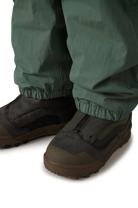 686 Men's Dojo Shell Pant in sage green with elasticated cuffs over snow boots