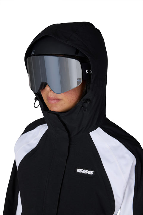 686 Women's Hologram Shell Jacket in black and white with hood up and ski goggles