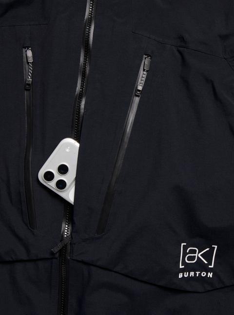 Burton [ak] black GORE-TEX jacket with multiple zippers and white iPhone in pocket
