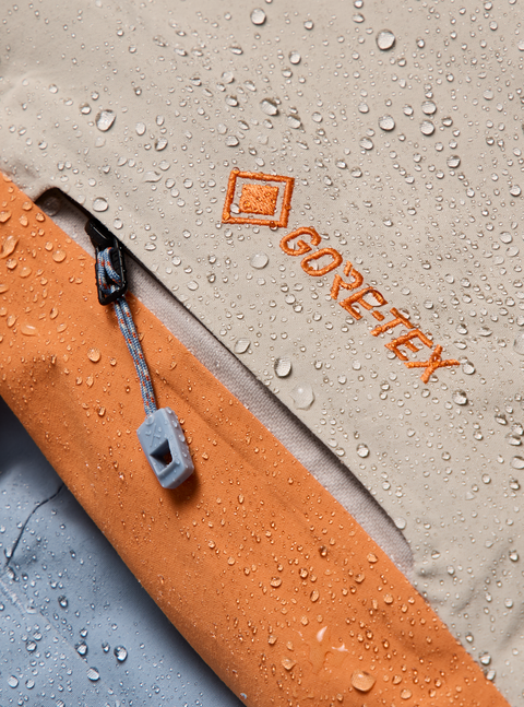 Burton ak GORE-TEX jacket close-up showing tan and orange fabric with water beading