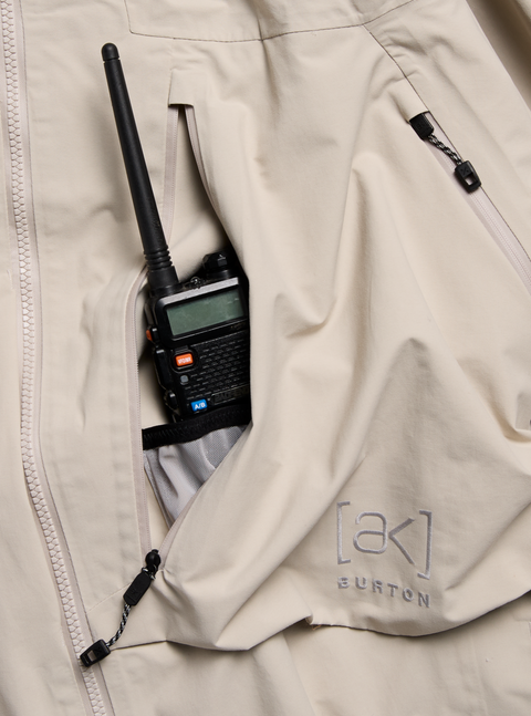 Beige Burton [ak] jacket chest pocket holding a walkie-talkie with antenna