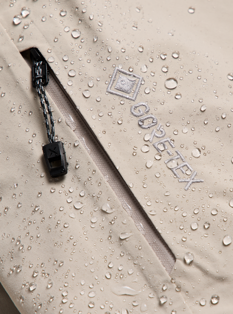 Close-up of beige GORE-TEX jacket with water beading on fabric near zipper
