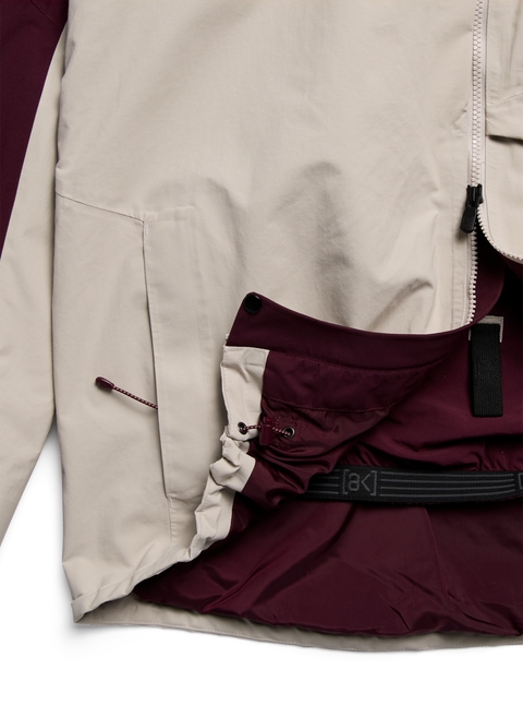 Burton ak Cyclic GORE-TEX jacket detail showing beige exterior, burgundy inner snow skirt, and belt.