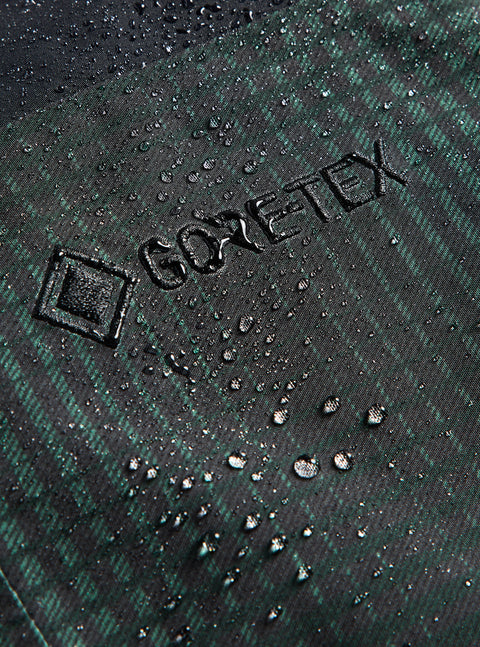 Gore-Tex logo embossed on dark green plaid waterproof fabric with beading water droplets