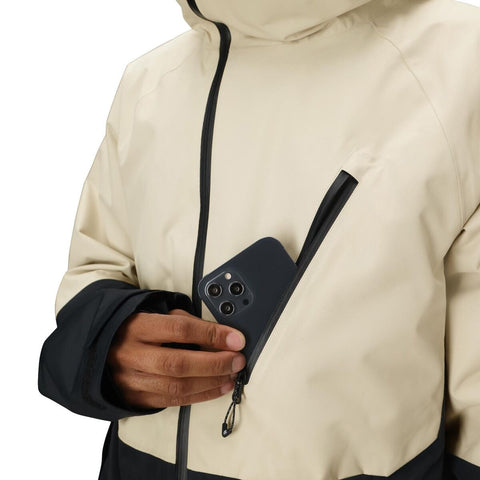 Close-up of a hand placing a smartphone into a chest pocket of a two-tone hooded jacket
