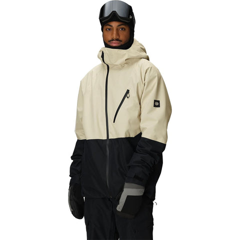 Man wearing two-tone ski jacket with hood and goggles in studio setting