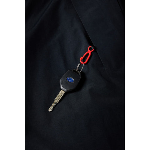 Close-up detail of black pant pocket with Subaru key clipped via red carabiner