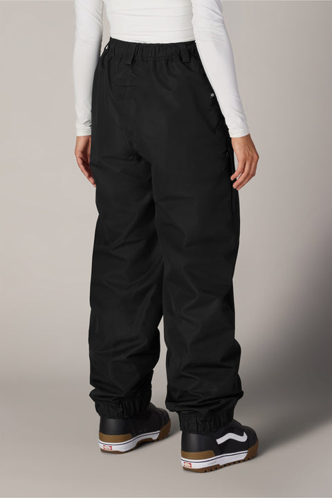 Women's black shell snow pants back view with cargo pocket and Vans boots