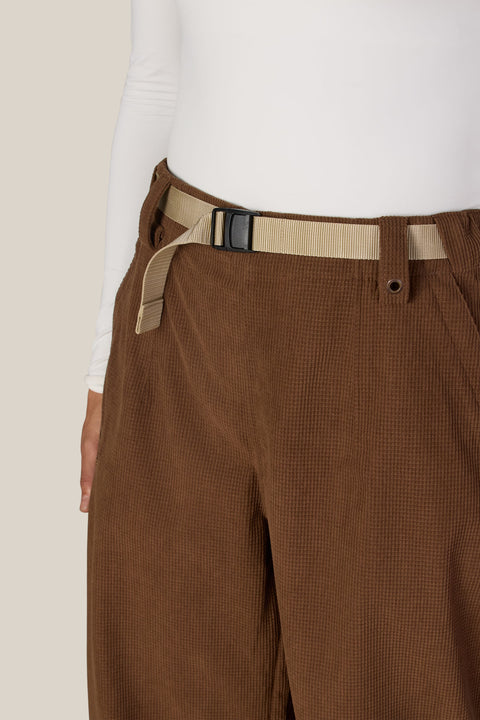 Close-up detail of women's wide-leg shell pants with tan webbing belt and buckle