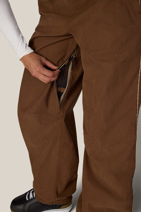 Close-up detail of brown corduroy shell pant showing zippered thigh ventilation pocket