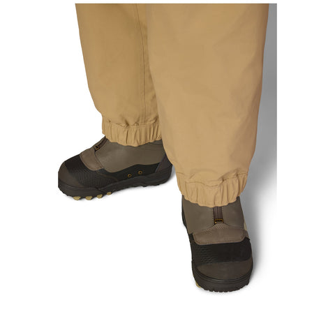 Close-up detail of women's snow pants hem and wading boots on white background