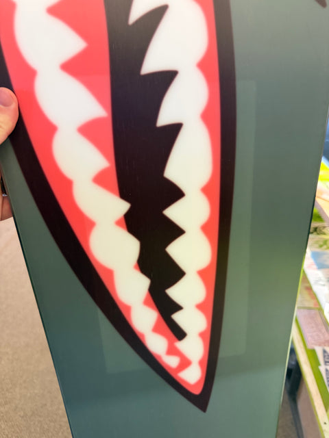 Bataleon Tornado snowboard with shark mouth graphic on olive green base