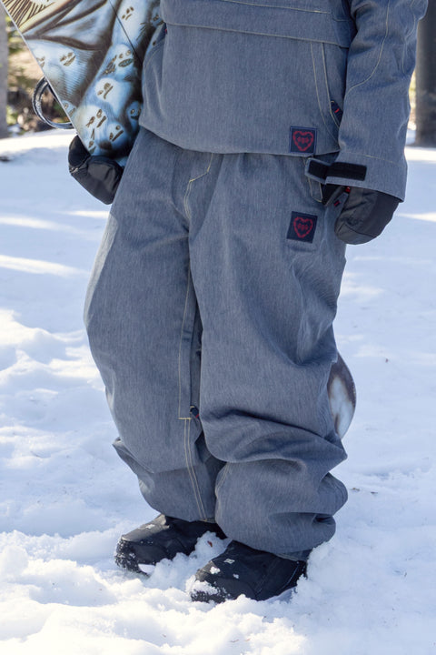 686 women's gray denim-look shell snow pants with heart logo patch and black boots
