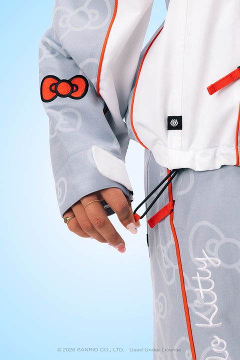 686 x Hello Kitty gray shell jacket sleeve with red bow patch and orange trim