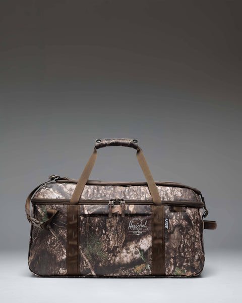 Herschel duffle bag in woodland camouflage print with brown handles and front zip pocket