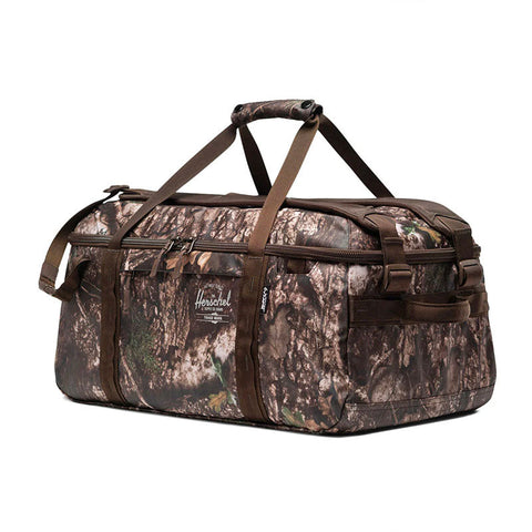 Herschel duffle bag in woodland camouflage pattern with brown straps and top carry handles