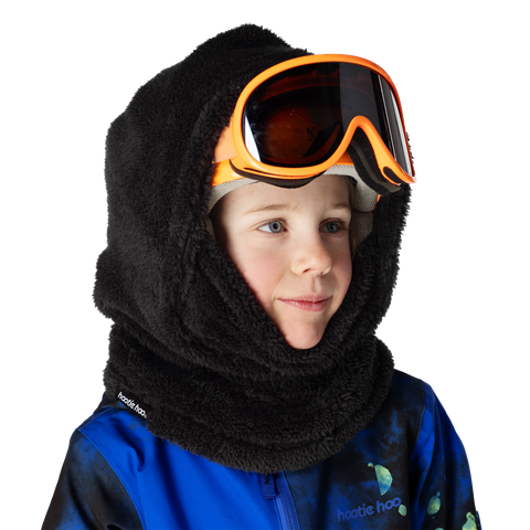 Child wearing black fleece balaclava hood with orange ski goggles and blue jacket