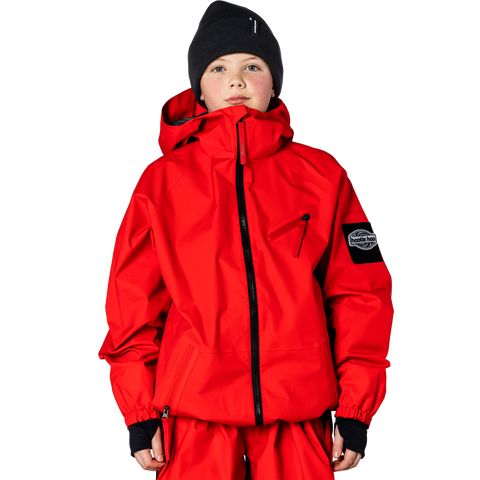 Child wearing a bright red hooded shell jacket with black zipper and brand patch on sleeve
