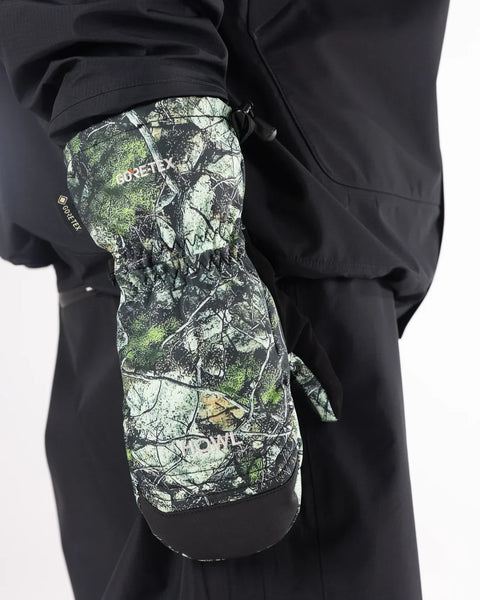 Howl Gore-Tex mitten in woodland camouflage pattern worn on hand against black jacket