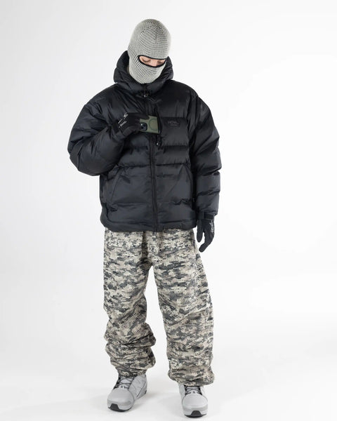Male model wearing Howl black puffer jacket with camo snow pants and knit balaclava