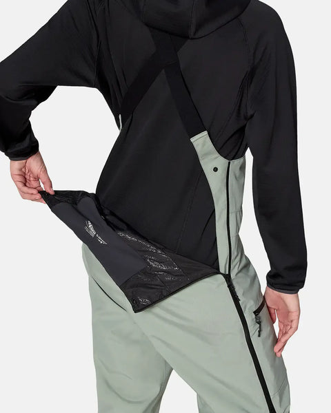Back detail view of women's insulated bib pant showing powder skirt and waistband construction