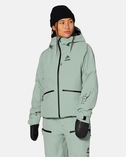 Woman wearing Jones Snowboards insulated ski jacket with hood and matching pants, front view