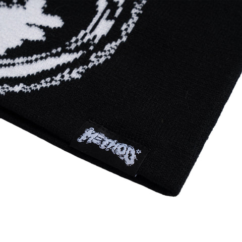 Close-up detail of black knitted beanie showing Method Mag woven label and jacquard pattern