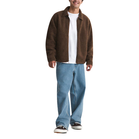 Man wearing brown sherpa zip-up jacket over white tee with light blue baggy jeans
